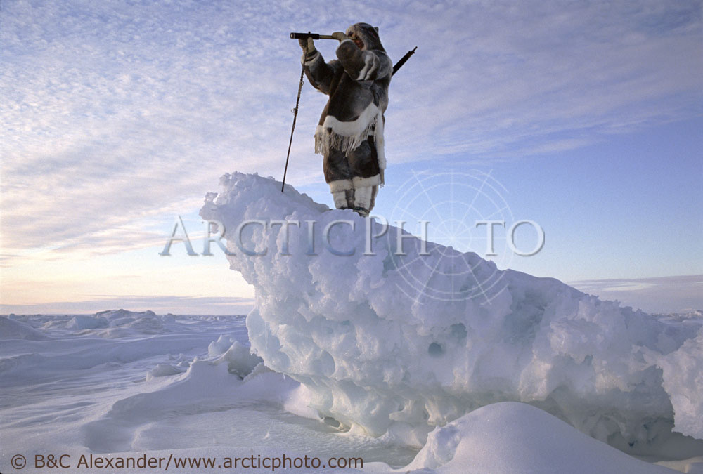 David Qaunaq, using a telescope to search for game while out hunting near Igloolik. Nunavut, Canada. (1995)