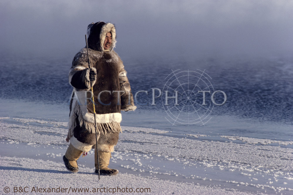 Louis Teperdjuk, an Inuit hunter, dressed in traditional fur clothing, walks along the floe edge. Igloolik, Nunavut, Canada. (1990)