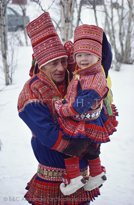 Sami father,Johan Eira,holds his son, Mikkel at a wedding in Kautokeino. They are dressed in traditional costume. Kautokeino, Finnmark Norway. (1985)